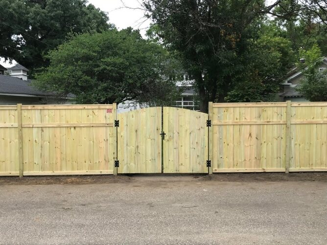Wooden privacy fence with double gate installed across a driveway, providing secure access to a residential yard.
