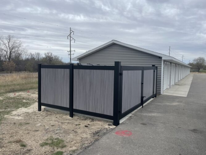 Commercial privacy panel fence with double gate installed around a utility area near a building.