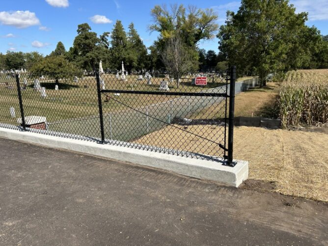Black chain link fence installed along a sidewalk