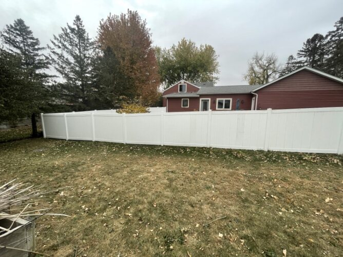 White vinyl privacy fence installed along the side of a house