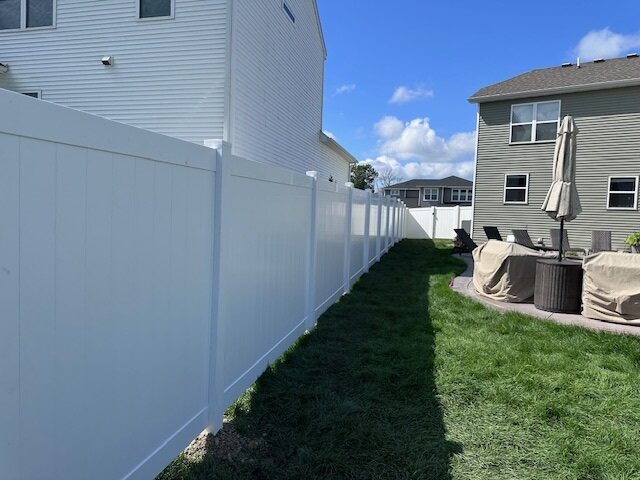 White vinyl privacy fence installed along the side of a house